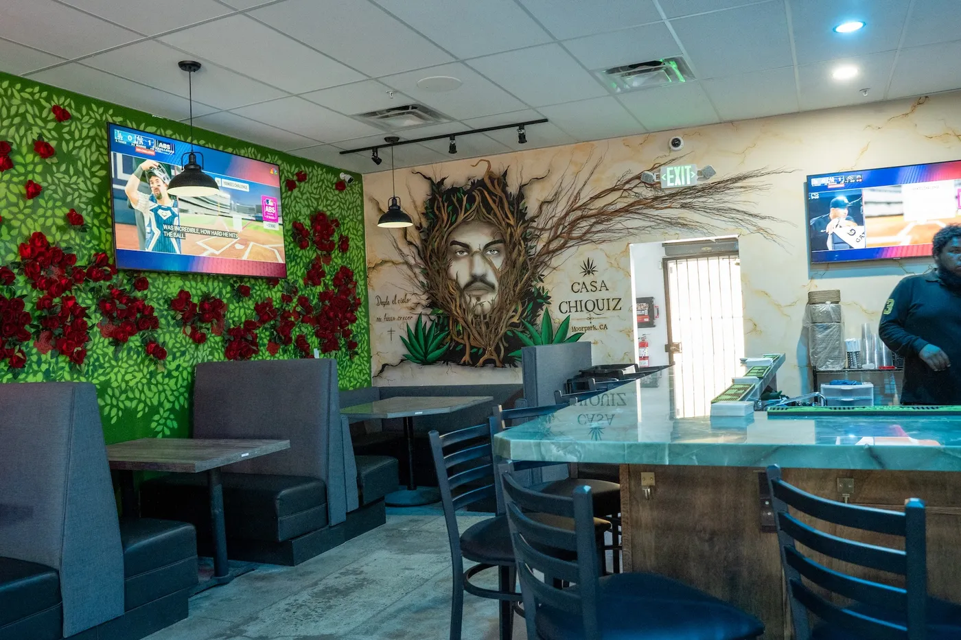 Booth seating along the rose hedge wall with agave face mural and bar counter